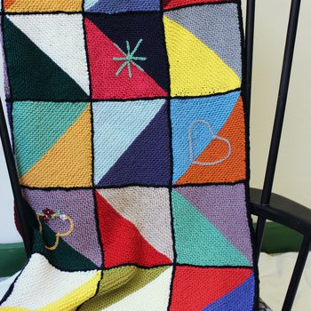 A knitted blanket with a multi coloured zig zag pattern