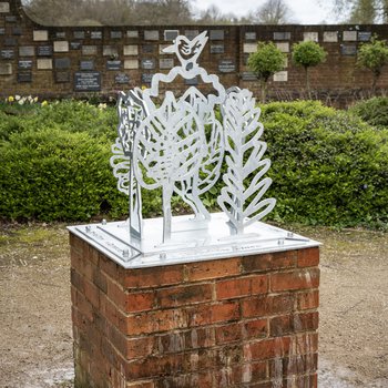 A metal sculpture of trees on a brick plinth