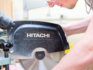 A student in safety goggles using a Hitachi electric saw blade.