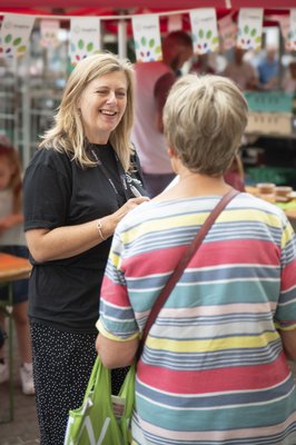 A woman from Inspire speaking to a customer at a market stall outside