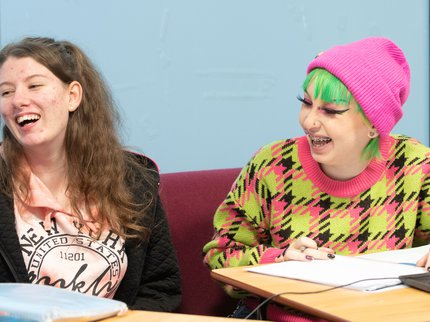 Two Inspire College students laughing in class.