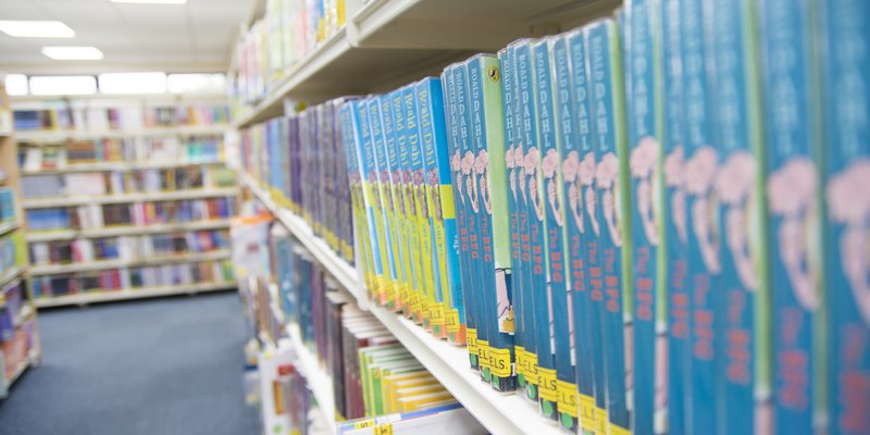 A close up shot of a shelf of blue books