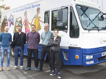 A group of authors stand outside of the ELS mobile library van