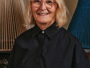 Portrait photograph of Jane Withers wearing a black shirt, glasses with blonde hair