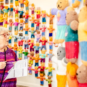 A woman with grey hair looks at the exhibition wall of brave bears