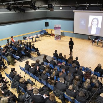School assembly in a hall with author Sufiya Ahmed standing at the front