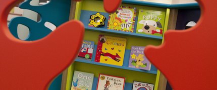 A shelf of board books, visible through a splat-shaped cut out