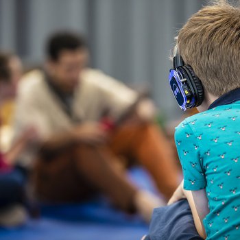 A child wearing a blue t shirt and headphones.