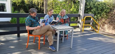 Three people reading around a table in Retford Library's garden