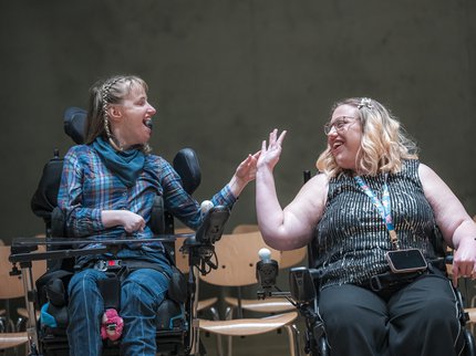 two women smiling and raising their arm towards each other