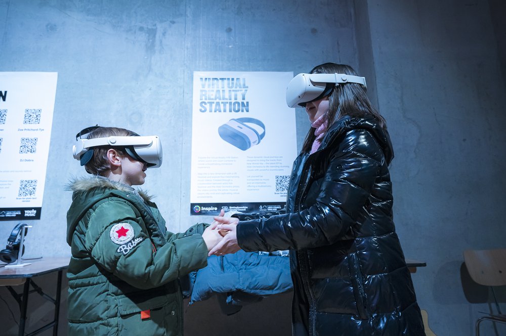 Two young people holding hands with white VR headsets on