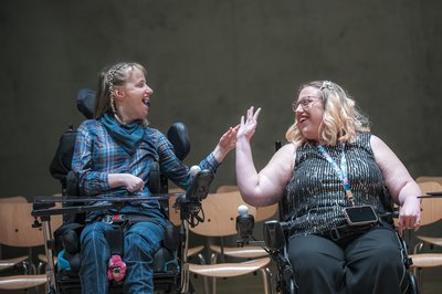 two women smiling and raising their arm towards each other