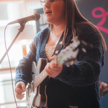 A girl playing the guitar and singing
