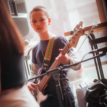 A young person playing guitar in a bar