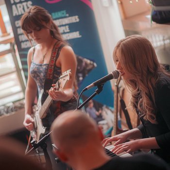 Two girls playing guitars in a bar