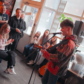 A boy playing guitar and singing to a bar full of people