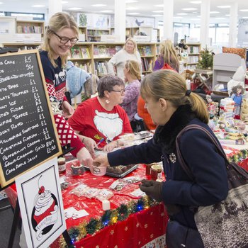 A group of customers looking at a christmas market stall, featuring baked goods