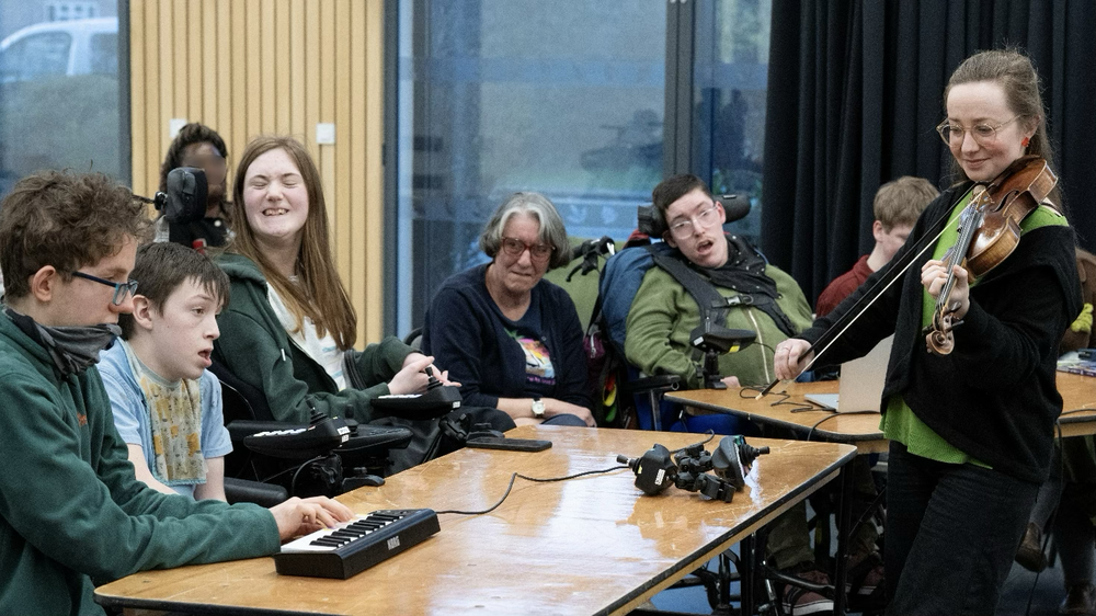 Able Orchestra mambers sat around a table taking part in a music making session.