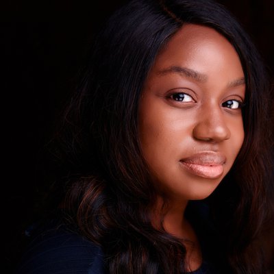 A headshot of author Abiola Bello - a young Black woman with long dark hair
