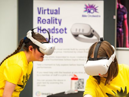 Two people wearing VR headsets and yellow T Shirts.
