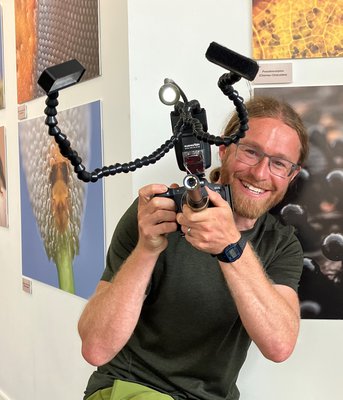 Image of Alex Hyde Photographer with his camera in front of his photographs