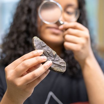 Young female examining an item with a magnifying glass