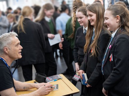 Three school children getting their books signed with an author
