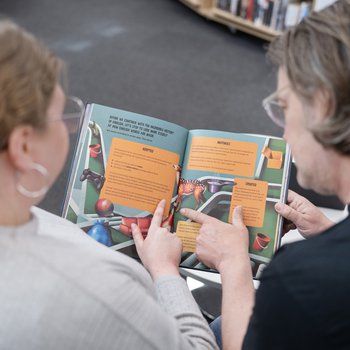 The back of heads of two adults reading a book.