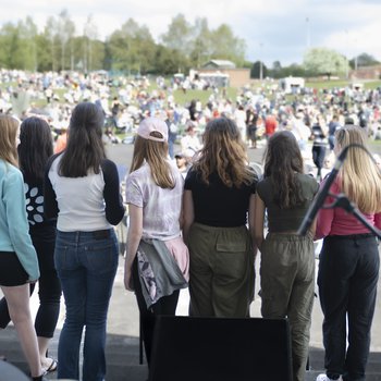 Rear view of young people on stage looking out over the audience at an open air concert
