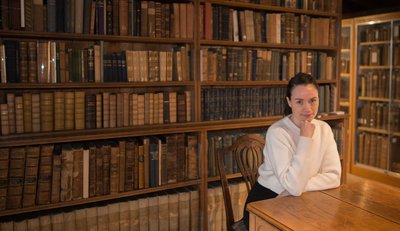 Image of author, Blessin Adams in a library.