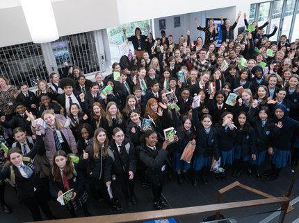 A large group of children holding up books and smiling