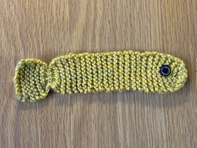 A knitted fish bookmark with a button eye