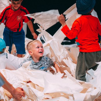 Children playing in lots of white paper.