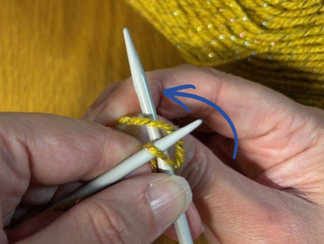 Photo of the working yarn being wrapped anti-clockwise around the right-hand knitting needle