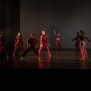 Eight dancers wearing red performing on stage