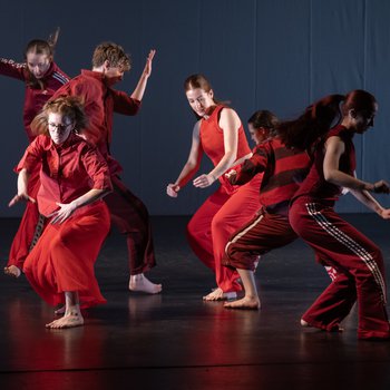 six young dancers wearing red outfits dancing on stage