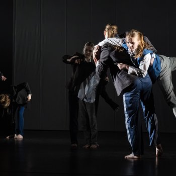 Six young dancers on stage. One dancer is lifting another on her back.