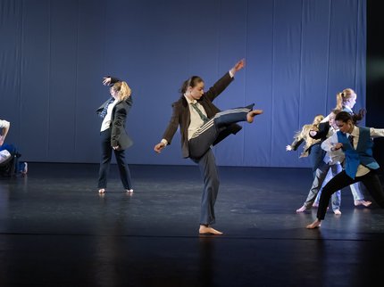 Six young dancers on stage. The front dancer is kicking her right leg in to the air.
