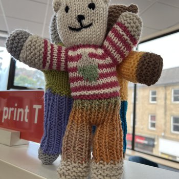 A knitted bear with a stripy jumper