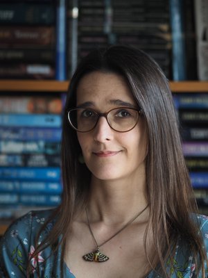 Headshot of Charlotte Strong, with glasses, brunette hair and a blue top