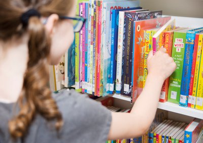 Child selecting book from a shelf.