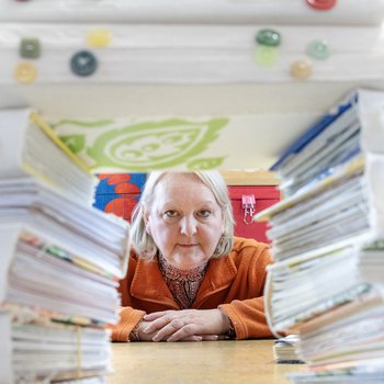 Christina is peeping through a stack of her hand made books which are stacked on the table in front of her