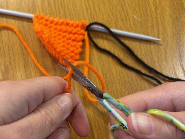 Image of a pair of scissors cutting yarn