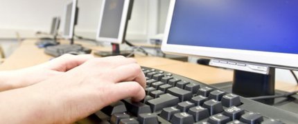 hands typing on keyboard in front of a computer screen