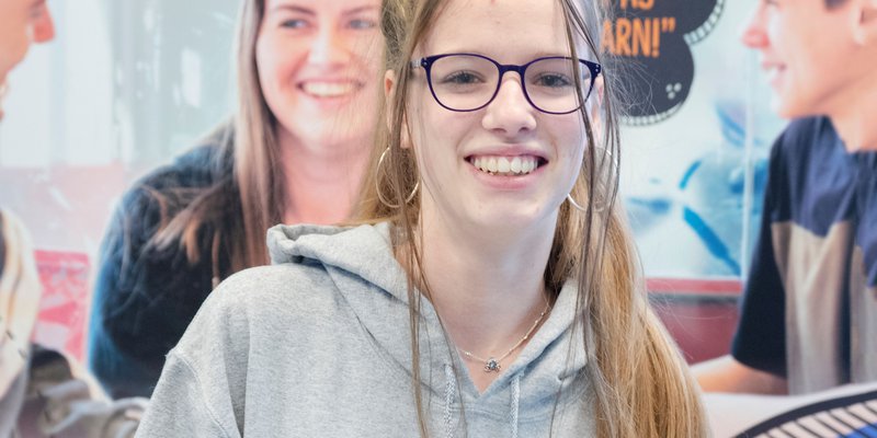 An Inspire College student wearing a hoodie with the college logo on the front.