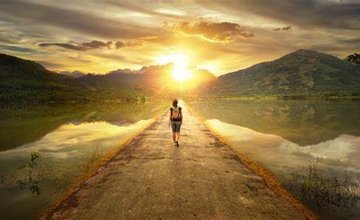 Person walking towards hills and sun