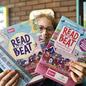A young girl holding Read to the Beat Summer Reading Challenge leaflets