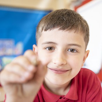 Young boy from Jesse Gray Primary School holding a pencil up to the camera