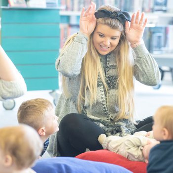 Mother surrounded by young children, making ears with her hands