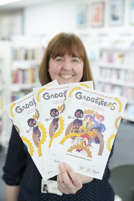 Lady in library holding Gadgeteers leaflets